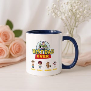 May include: A white ceramic mug with a dark blue interior and handle. The front features a graphic of Buzz Lightyear above the text BEST DAD EVER, followed by small character illustrations of Woody, Jessie, Bullseye, and Forky with names below.