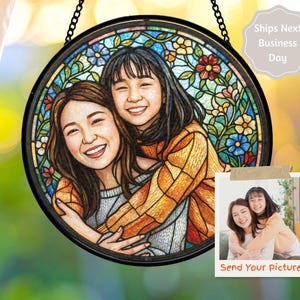 May include: Round stained glass art piece featuring a portrait of two smiling people, surrounded by a floral border. The artwork is framed in black and hangs from a chain. A small photo is attached with the text "Send Your picture".