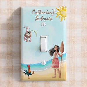 May include: A rectangular light switch cover featuring a light blue sky, a yellow sun, and a beach scene with a character holding a wooden oar, a small rooster, and a coconut creature. The text Catherine's Bedroom is printed in brown script.