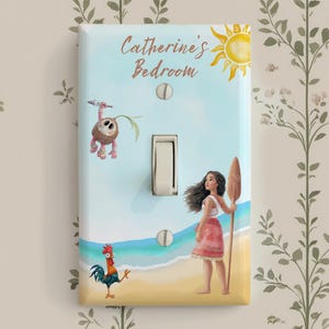 May include: A rectangular light switch cover featuring a beach scene with a cartoon girl holding a wooden oar, a small rooster, and a coconut creature. The text Catherine's Bedroom is printed at the top with a yellow sun illustration.