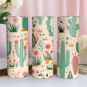May include: Three cylindrical tumblers featuring a repeating pattern of various green cacti and pink desert flowers on a light beige background. The design includes tall saguaro cacti, round prickly pear cacti, and small succulents with pink blooms.