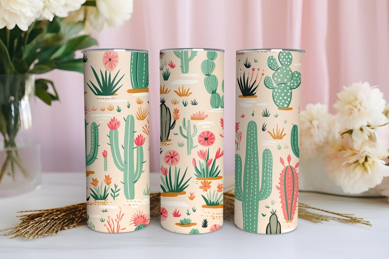 May include: Three cylindrical tumblers featuring a repeating pattern of various green cacti and pink desert flowers on a light beige background. The design includes tall saguaro cacti, round prickly pear cacti, and small succulents with pink blooms.