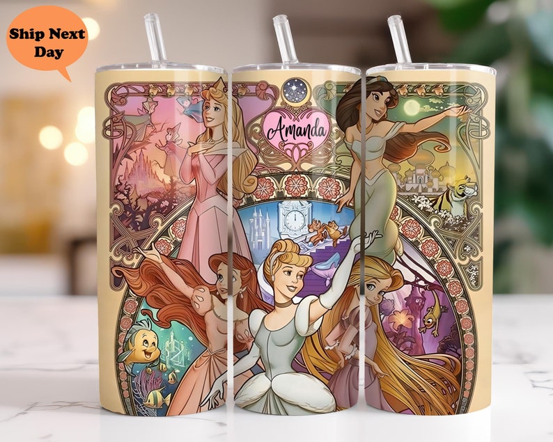 Op de afbeelding: Een set van drie roestvrijstalen bekers met een kleurrijk ontwerp met Disney-prinsessen. De bekers hebben een gouden rand en bodem. Het ontwerp omvat Assepoester, Rapunzel, Ariel, Jasmine en Aurora. De tekst "Amanda" staat op een van de bekers.