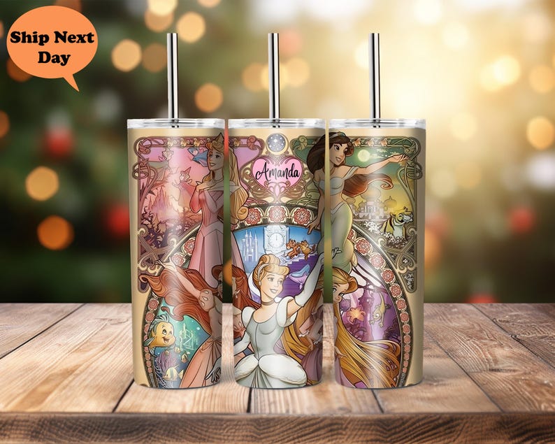 Op de afbeelding: Drie roestvrijstalen bekers met deksels en rietjes. Elke beker heeft een andere Disney-prinses: Ariel, Assepoester en Rapunzel. De bekers hebben een gouden achtergrond met een bloemmotief. De tekst "Amanda" staat op de Assepoester-beker.