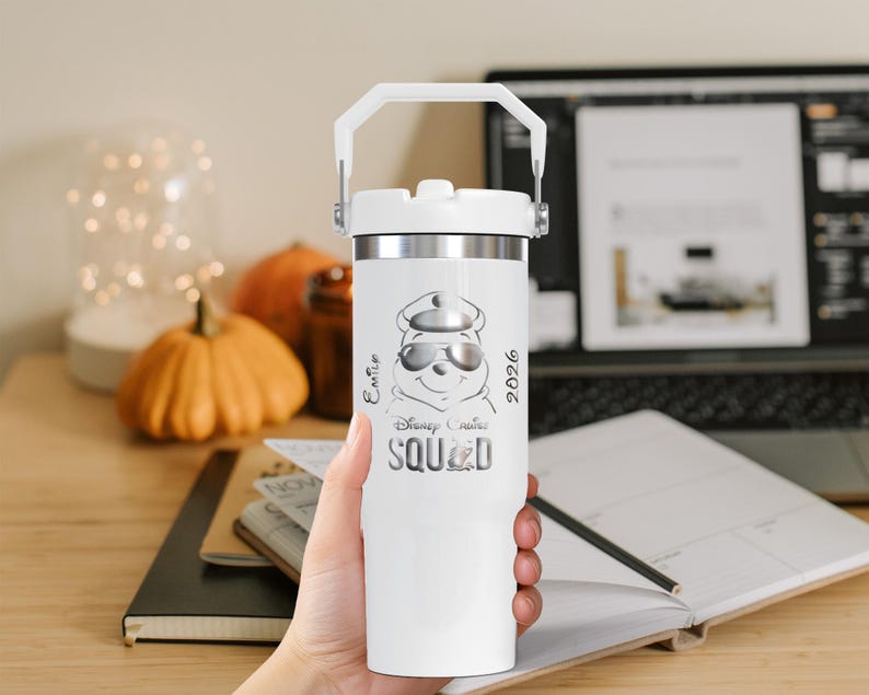 Puede incluir: Un vaso t&eacute;rmico blanco con borde y asa plateados. Presenta un gr&aacute;fico de Winnie the Pooh con gafas de sol y gorra, con el texto "Disney Cruise Squad 2026". El vaso est&aacute; sostenido en una mano.