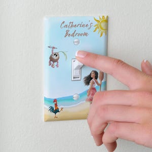 May include: A rectangular light switch cover plate featuring a Moana-themed design with a beach scene, a rooster, a small creature, and a yellow sun. The text "Catherine's Bedroom" is printed at the top in brown script. The plate is white with two screws.