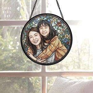 May include: A round, stained glass window art piece featuring a portrait of two smiling people embracing. The artwork is surrounded by a floral design in various colors and is framed in black. The text "SHIPS NEXT DAY" is visible.