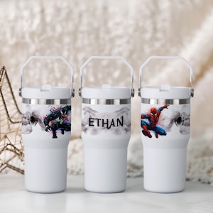 Peut inclure: Trois gobelets isothermes blancs avec des rebords argentés et des poignées blanches. L'un présente Venom, un autre porte le nom "ETHAN", et le troisième affiche Spider-Man. Chaque gobelet a un motif d'araignée noir.