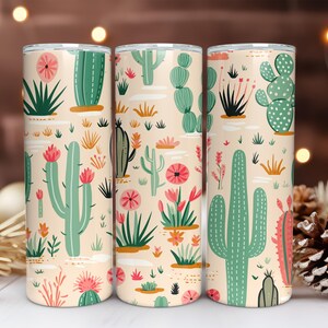 May include: Three cylindrical tumblers featuring a repeating pattern of various green cacti and pink flowers on a light beige background. The design includes tall saguaro-style cacti, round prickly pear cacti, and small desert succulents.