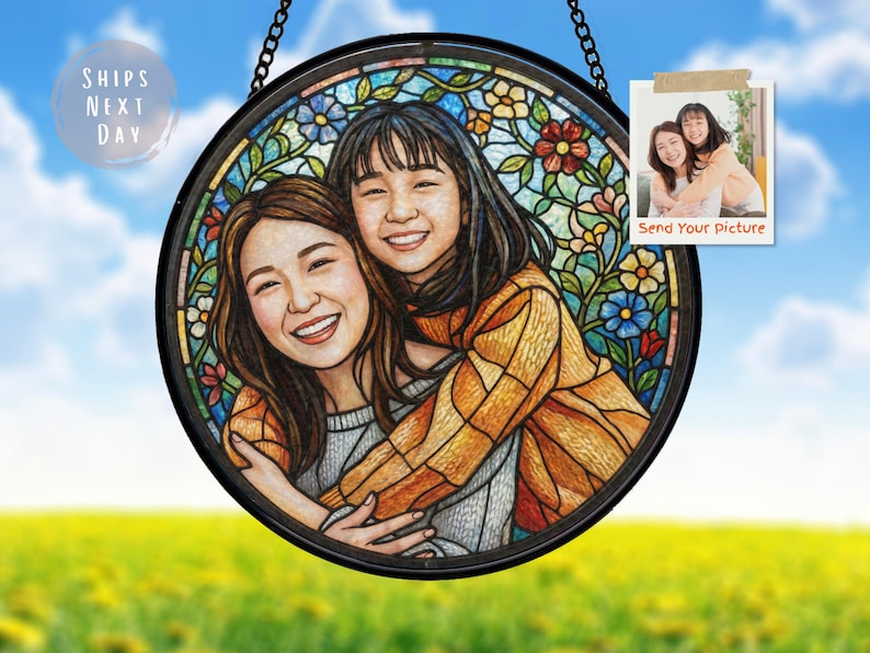 May include: Round stained glass art piece featuring a portrait of two smiling people, surrounded by a floral design. The artwork is framed in black and hangs from a chain. The text "Send Your Picture" is visible.