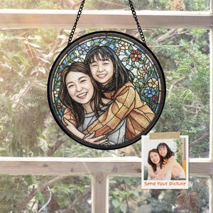 May include: A round stained glass window with a black frame, depicting two smiling women embracing. The background features colorful floral patterns. A small photo with the text "Send Your Picture" is attached.