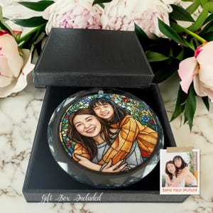 May include: A round, clear crystal ornament with a stained-glass style image of two smiling people hugging, presented in a black gift box. The ornament is surrounded by pink and white peonies. Text on the box reads "Gift Box Included."