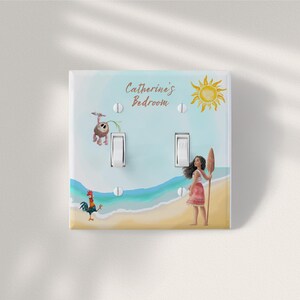 May include: A double light switch cover plate featuring a beach scene with a cartoon girl holding an oar, a rooster, and a small creature. The text "Catherine's Bedroom" is printed at the top, accompanied by a yellow sun illustration against a blue sky.