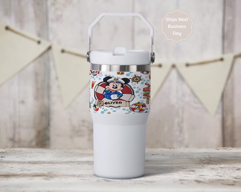 May include: White insulated tumbler with a handle and a decorative band featuring a cartoon Mickey Mouse in a sailor outfit. The band includes the name "Oliver" and nautical elements like life preservers and anchors.