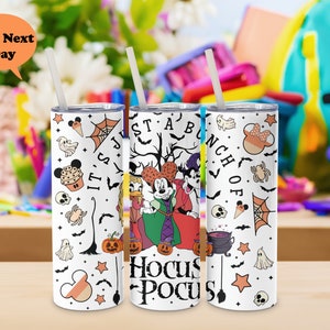 Puede incluir: Un vaso de acero inoxidable blanco con un tema de Halloween con Mickey Mouse, Minnie Mouse y Donald Duck vestidos con disfraces. El vaso tiene una variedad de gr&aacute;ficos de tem&aacute;tica de Halloween, incluyendo calabazas, murci&eacute;lagos, fantasmas y un caldero. El texto "It's Just A Bunch Of Hocus Pocus" est&aacute; impreso en el vaso.