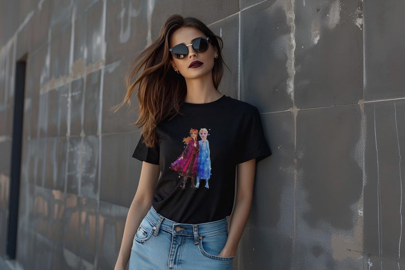 May include: Black t-shirt featuring a watercolor image of two animated characters in red and blue dresses. The t-shirt is worn by a person wearing sunglasses and blue jeans.