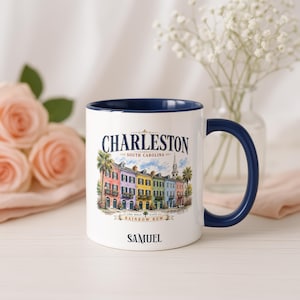 May include: A white ceramic mug with a dark blue interior and handle. The front features a colorful illustration of Charleston, South Carolina's Rainbow Row with palm trees and a steeple. Text reads Charleston, South Carolina, Rainbow Row, and Samuel.