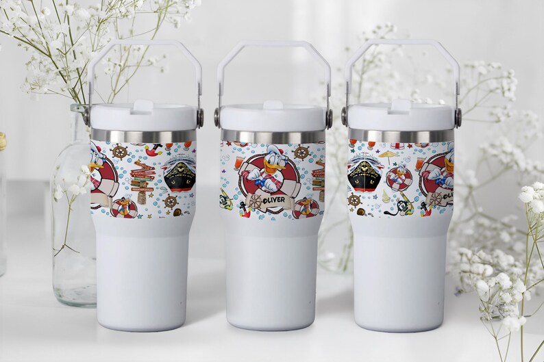 May include: Three white insulated tumblers with a handle. Each tumbler features a wrap-around design with nautical elements, including a cruise ship, Donald Duck in a life preserver, and the name "Oliver".