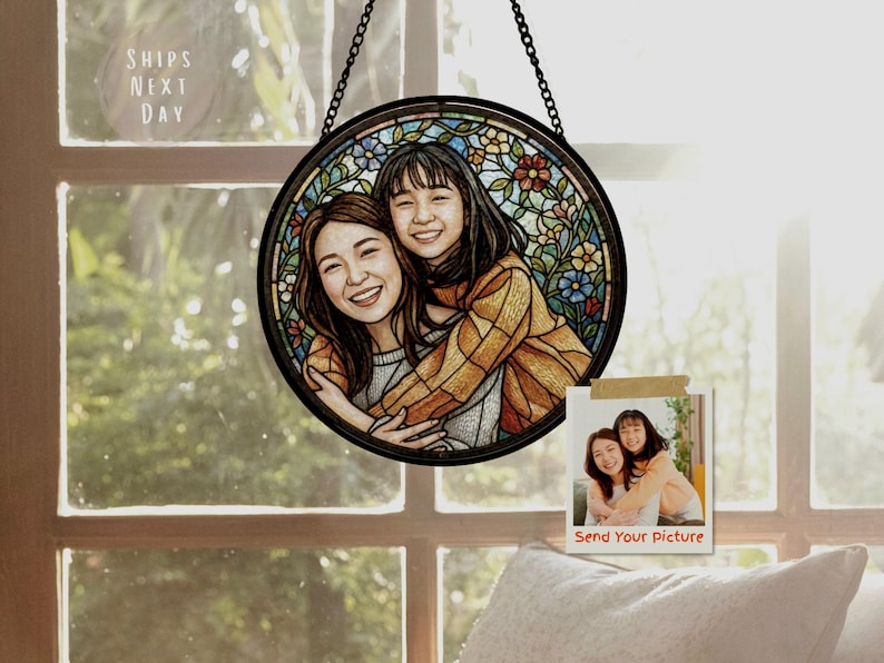 May include: A round, stained-glass style portrait of two smiling people, framed in black and hanging from a chain. The image is set against a window. A small photo with the text "Send Your Picture" is also visible.