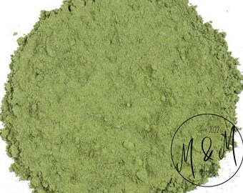 May include: A close-up of a pile of finely ground, light green powder. The powder is in a shallow bowl and is evenly distributed. The powder is likely a dried herb or spice.