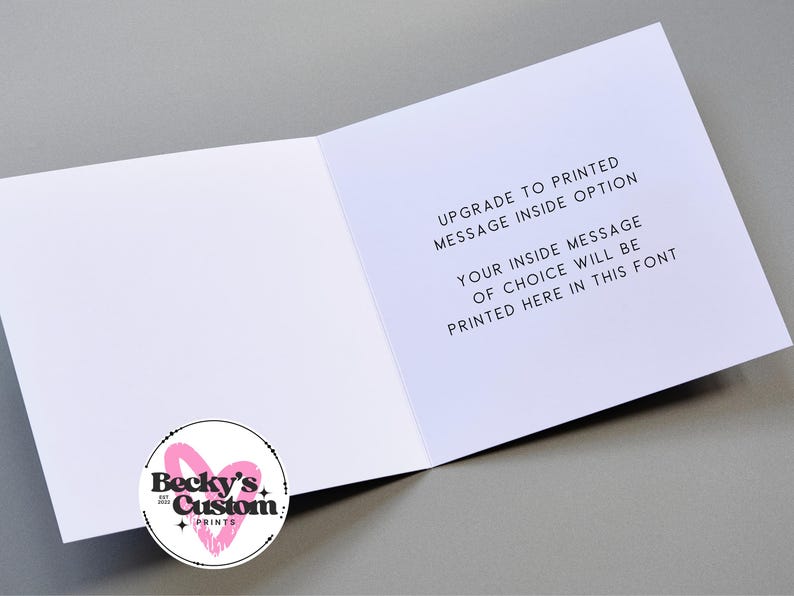 Op de afbeelding: Een open witte wenskaart met tekst: "UPGRADE TO PRINTED MESSAGE INSIDE OPTION" en "YOUR INSIDE MESSAGE OF CHOICE WILL BE PRINTED HERE IN THIS FONT". Een cirkelvormig logo met "Becky's Custom Prints" is zichtbaar.