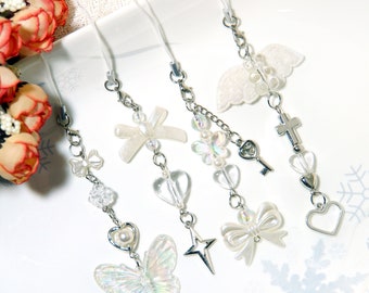 May include: Five different phone charms with various designs, including a butterfly, a star, a bow, a cross, and angel wings. Each charm is made of silver metal and clear beads.