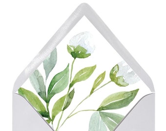 Pode incluir: Um envelope branco com um design floral na frente. O design apresenta flores brancas e folhas verdes em um estilo aquarela.