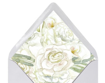 Pode incluir: Um envelope branco com um design floral na aba. O design apresenta flores brancas e verdes em aquarela.