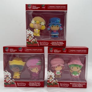 May include: Four boxed sets of Strawberry Shortcake flocked figures. Each box contains two figures with different characters and names, including Lemon Meringue, Blueberry Muffin, Orange Blossom, Raspberry Tart, Strawberry Shortcake, and Lime Chiffon.