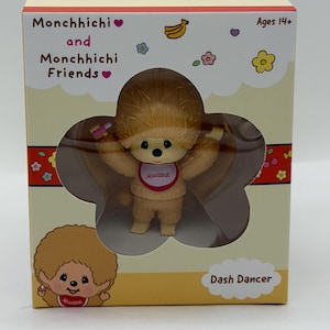 May include: A Monchhichi Dash Dancer figure in a box. The figure is light brown with a matching fur-like hairstyle and a bib. The box is beige with the words "Monchhichi and Monchhichi Friends" and "Dash Dancer" printed on it. The box also has a clear window.
