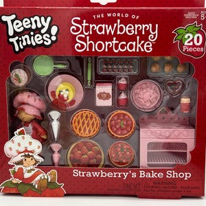May include: A boxed Strawberry Shortcake "Teeny Tinies" playset. The set includes a pink oven, miniature pies, cupcakes, and a Strawberry Shortcake figure. The box reads "Strawberry's Bake Shop" and "20 Pieces".
