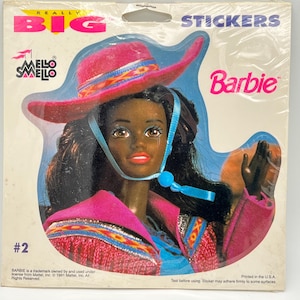 Puede incluir: Una pegatina con una muñeca Barbie que lleva un sombrero de vaquero rosa y una camisa con estampado azul y rosa. La pegatina forma parte de un conjunto de "Really Big Stickers" y está etiquetada con el número #2.