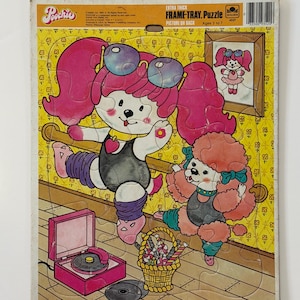 May include: A vintage Pochie frame-tray puzzle featuring cartoon poodle characters in a dance scene. The puzzle has a yellow background with a pink record player, a basket of candy, and the text "EXTRA THICK FRAME-TRAY Puzzle". Ages 3 to 7.