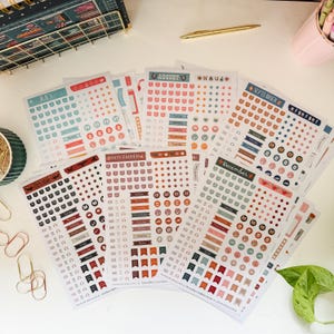 May include: A collection of planner stickers featuring calendar layouts and decorative elements for various months, including July, August, September, October, November, and December. The stickers are in various colors, with banners and circles.