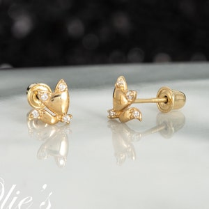 May include: A pair of gold stud earrings shaped like foxes, each featuring small clear stones set into the ears and tail. The earrings have a polished finish and include screw-back posts for secure fastening, displayed on a reflective surface.