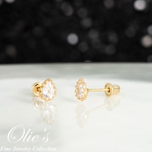 May include: A pair of gold teardrop-shaped earrings with clear cubic zirconia stones. The earrings have a screw-back closure.