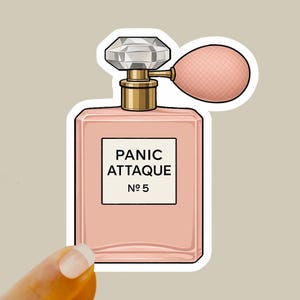 May include: A pink perfume bottle with a crystal-like stopper and a pink bulb atomizer. The label reads "PANIC ATTAQUE No 5". The bottle has a gold-colored neck and is a sticker.