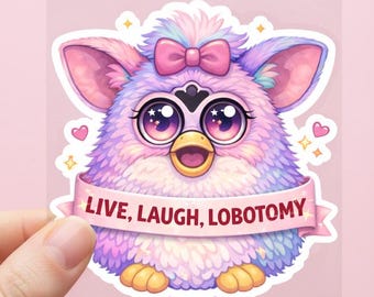 Op de afbeelding: Een sticker met een cartoonachtig Furby-achtig wezen in paars, roze en geel. Het wezen heeft grote, expressieve ogen, een roze strik en een banner met de tekst "LIVE, LAUGH, LOBOTOMY". De sticker wordt door een hand vastgehouden.