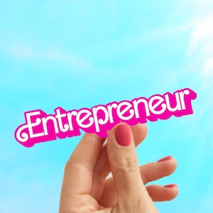 May include: A hand holds up a pink paper sign with the word "Entrepreneur" written in white letters against a blue sky background.