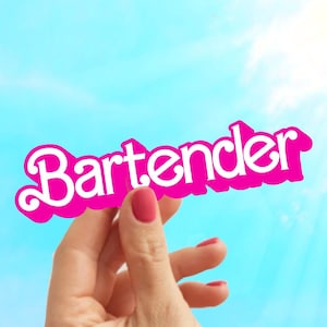 May include: A hand holding up a pink sign with the word "Bartender" written in white letters.