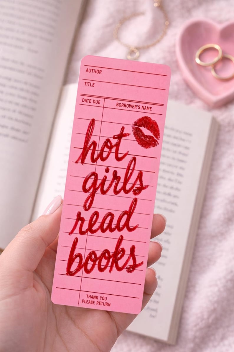 May include: Pink bookmark with the text "hot girls read books" in red script, along with a red lipstick kiss mark. The bookmark has lines for author, title, date due, and borrower's name.