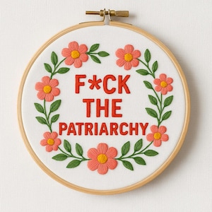 Peut inclure: Broderie sur toile dans un cercle de bois, avec l'inscription rouge "F*CK THE PATRIARCHY", entourée d'une couronne de fleurs corail et de feuilles vertes.