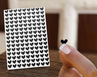 May include: A sheet of black heart stickers. The sheet is white and has a grid pattern of black hearts.