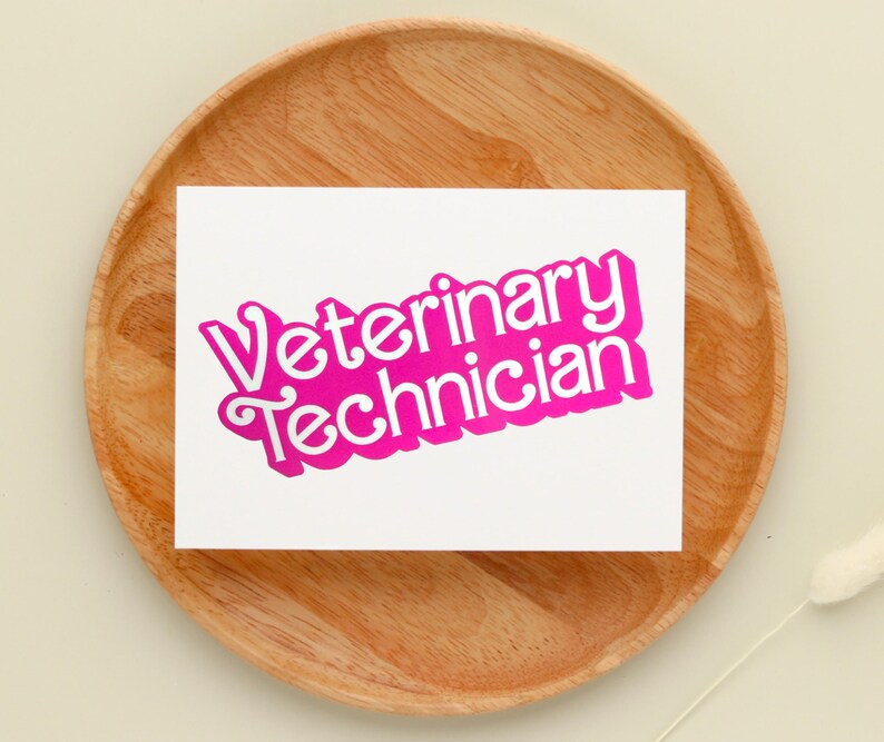 Op de afbeelding: Een witte kaart met de woorden "Veterinary Technician" in roze, in 3D-lettertype. De kaart ligt op een houten oppervlak.