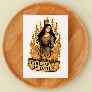 May include: A sticker featuring a woman in a dress surrounded by flames. The image has a vintage style with a banner at the bottom that reads "GIRLS WILL BE GIRLS". The color palette includes shades of brown, yellow, and orange.