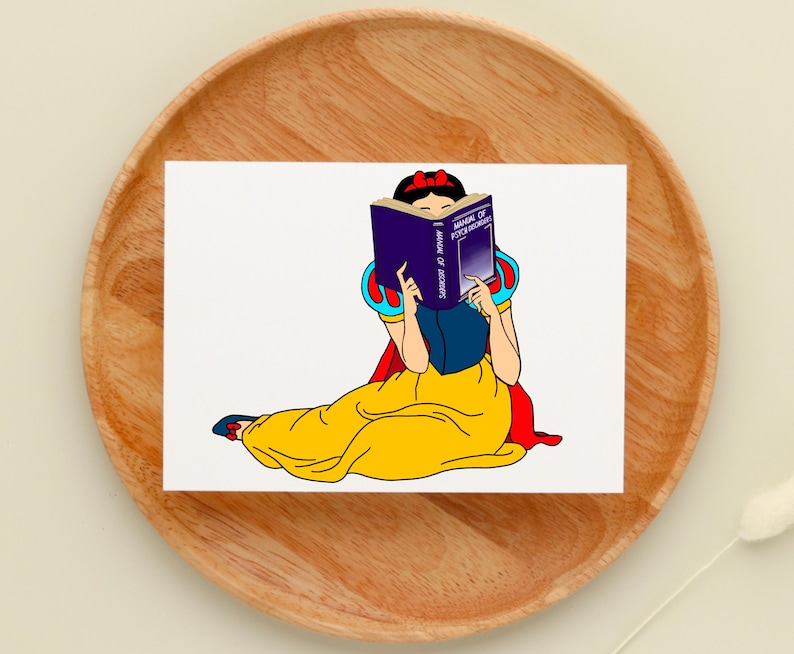May include: A cartoon illustration of Snow White sitting and reading a book titled "Manual of Psychology". She is wearing a yellow dress with a red cape and a blue sash. The book is purple with gold lettering.