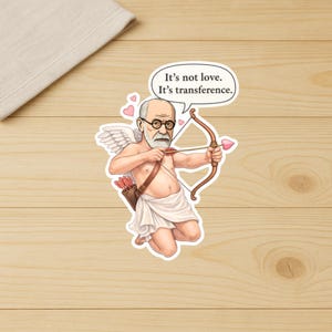 May include: A sticker featuring a cartoon of Sigmund Freud as Cupid, with wings and a bow and arrow. The speech bubble says, "It's not love. It's transference."