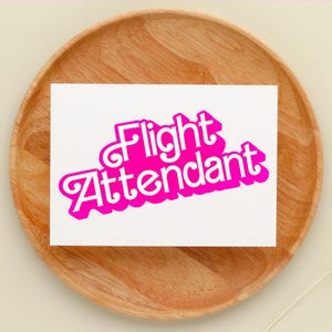 May include: A white card with the words "Flight Attendant" in pink, retro-style lettering.