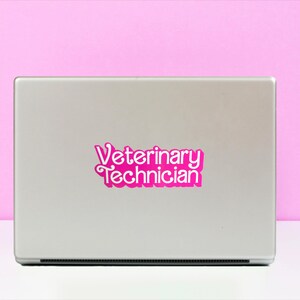 Op de afbeelding: Een zilveren laptop met een roze sticker waarop "Veterinary Technician" staat.
