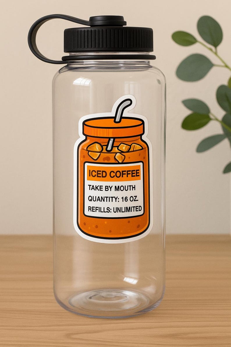 Peut inclure: Une bouteille d'eau transparente avec un couvercle et une poign&eacute;e noirs. Un autocollant orange de caf&eacute; glac&eacute; est appos&eacute; sur la bouteille, avec le texte "ICED COFFEE, TAKE BY MOUTH, QUANTITY: 473 ml, REFILLS: UNLIMITED."